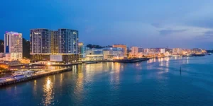 Night view of KK Waterfront with illuminated promenade, reflections on the water, and city lights- feature image for the blog: Filipino Market and KK Waterfront