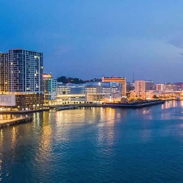 Night view of KK Waterfront with illuminated promenade, reflections on the water, and city lights- feature image for the blog: Filipino Market and KK Waterfront