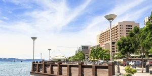 Daytime view of the Kota Kinabalu waterfront promenade under bright midday sunlight with seaside walkway and ocean views- feature image for walkable kota kinabalu blog