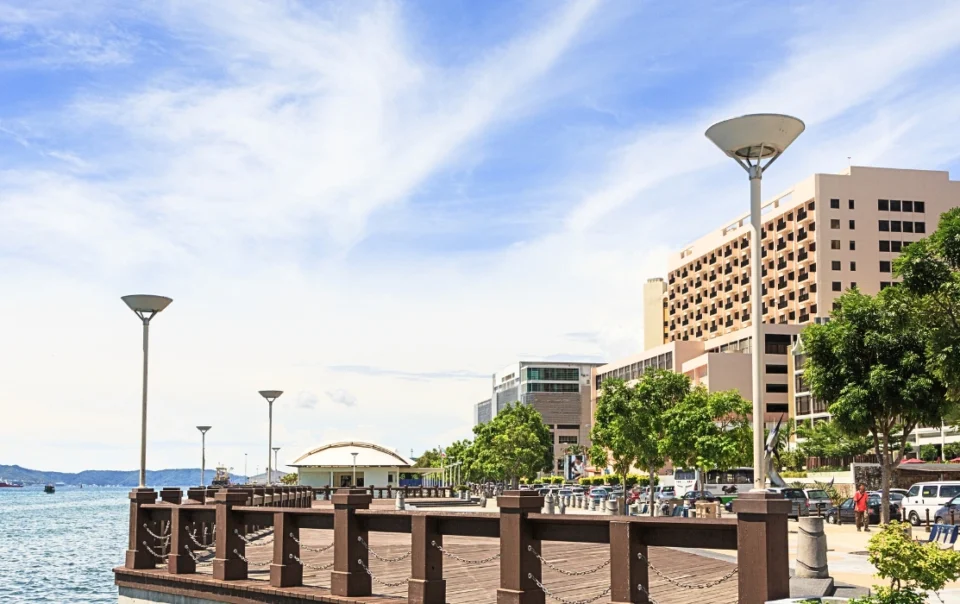 Daytime view of the Kota Kinabalu waterfront promenade under bright midday sunlight with seaside walkway and ocean views- feature image for walkable kota kinabalu blog