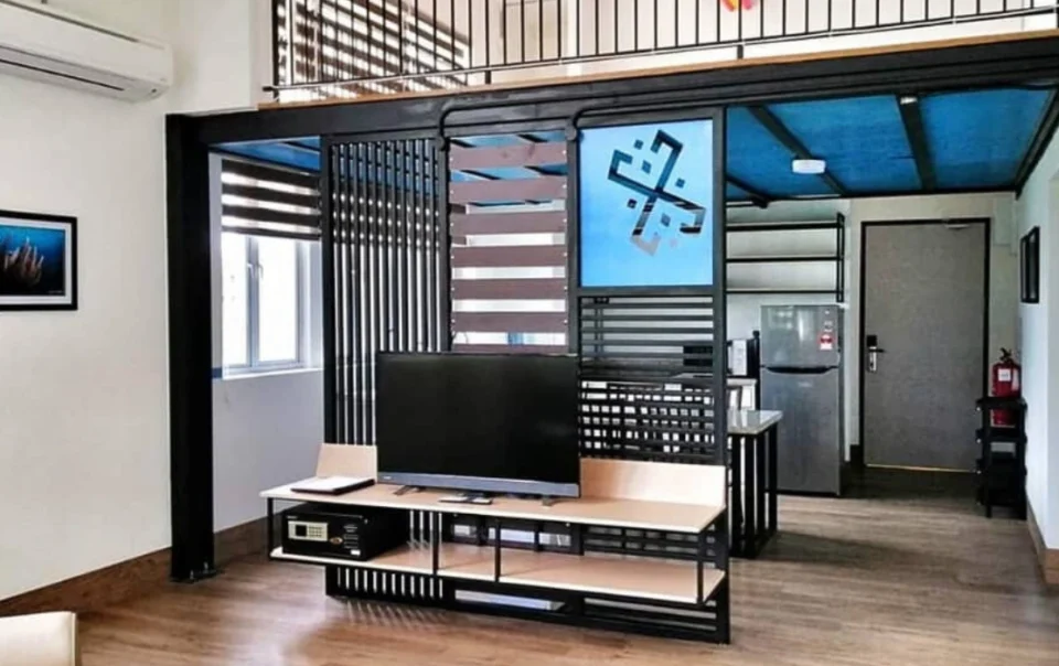 Open-concept living room and connected kitchen area in the Super Deluxe Apartment with Loft Type A at Polaris Suite, featuring a spacious and functional apartment layout.