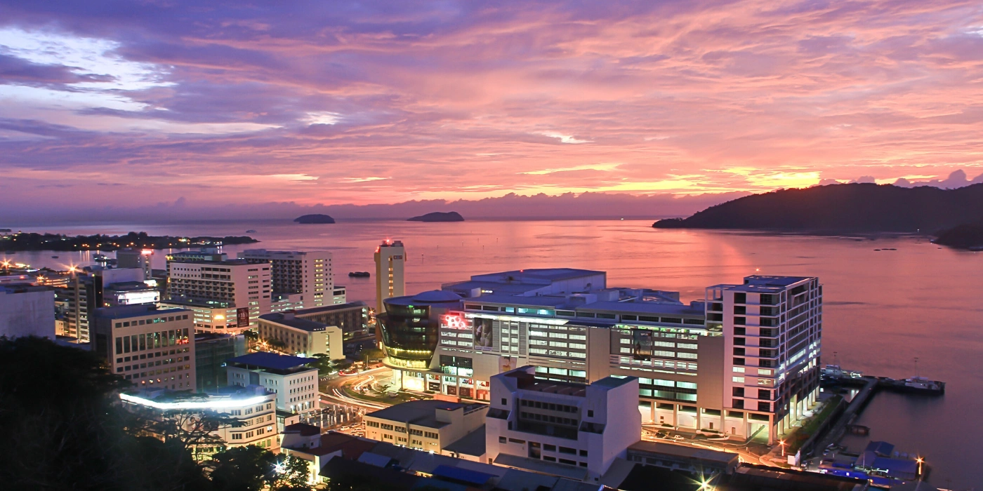 Kota Kinabalu city skyline by the sea just after sunset with a purple-blue sky